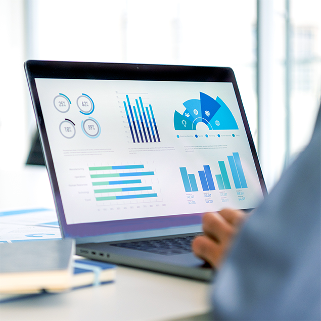 Photograph of a person's hand typing on a laptop that is displaying various data visualizations including circular progress charts, vertical bar graphs, a semi-circular gauge chart, and horizontal bar charts in blue and green tones. The charts present statistical data with percentage values and numerical labels, highlighting trends and comparisons across different categories.